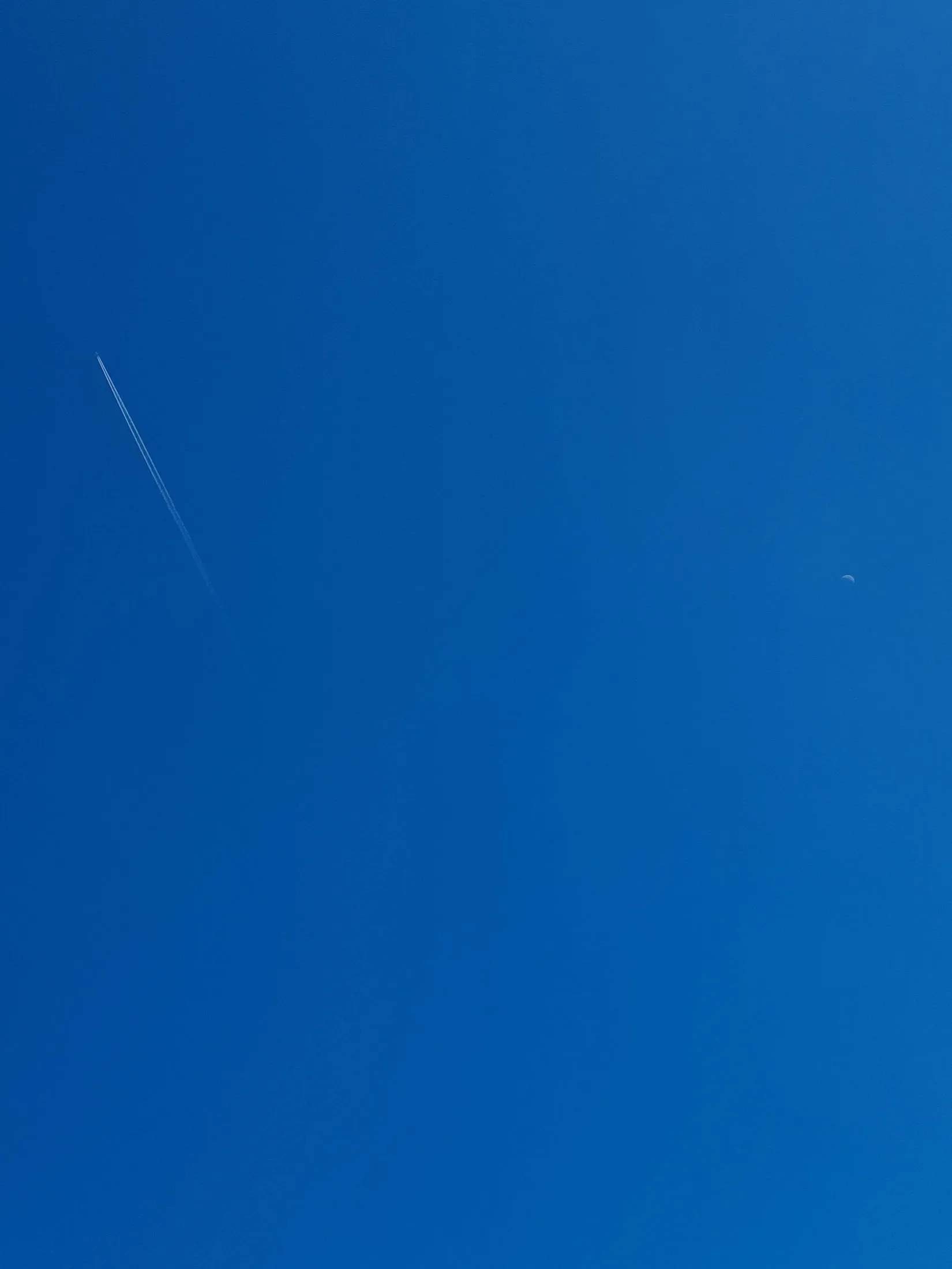 A clear blue sky with a faint trail
