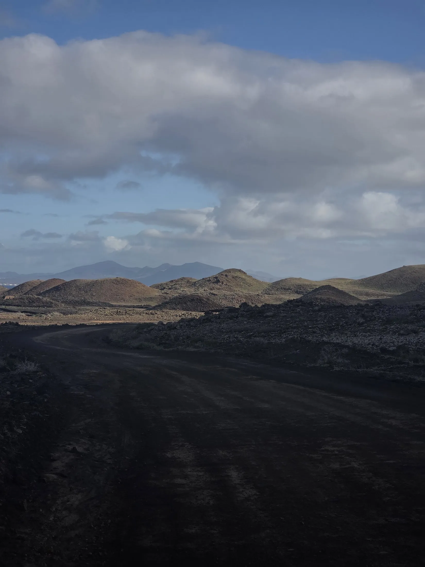 Dark lava toward pale hills and cloud