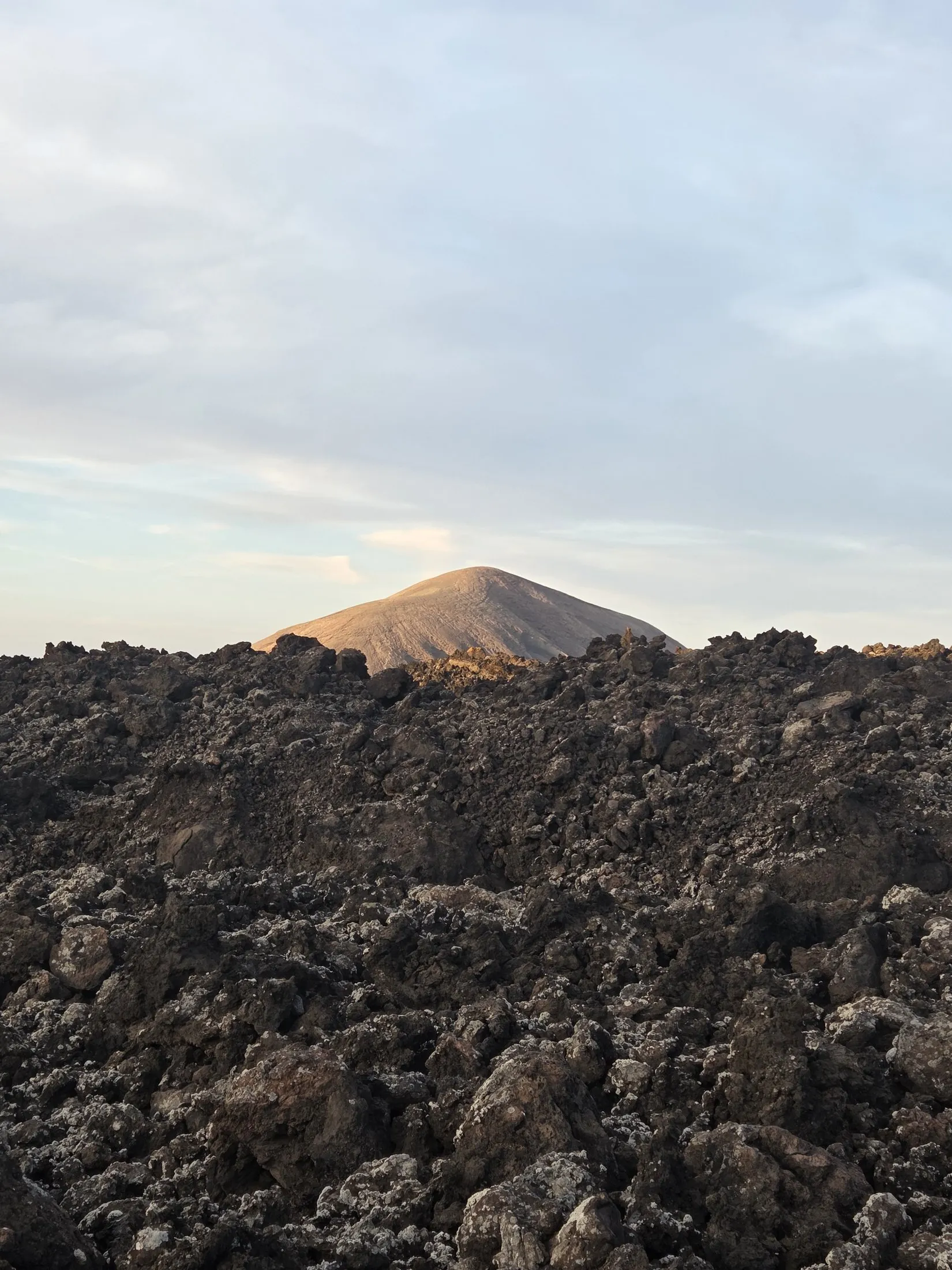 A pale cone beyond a field of lava rock