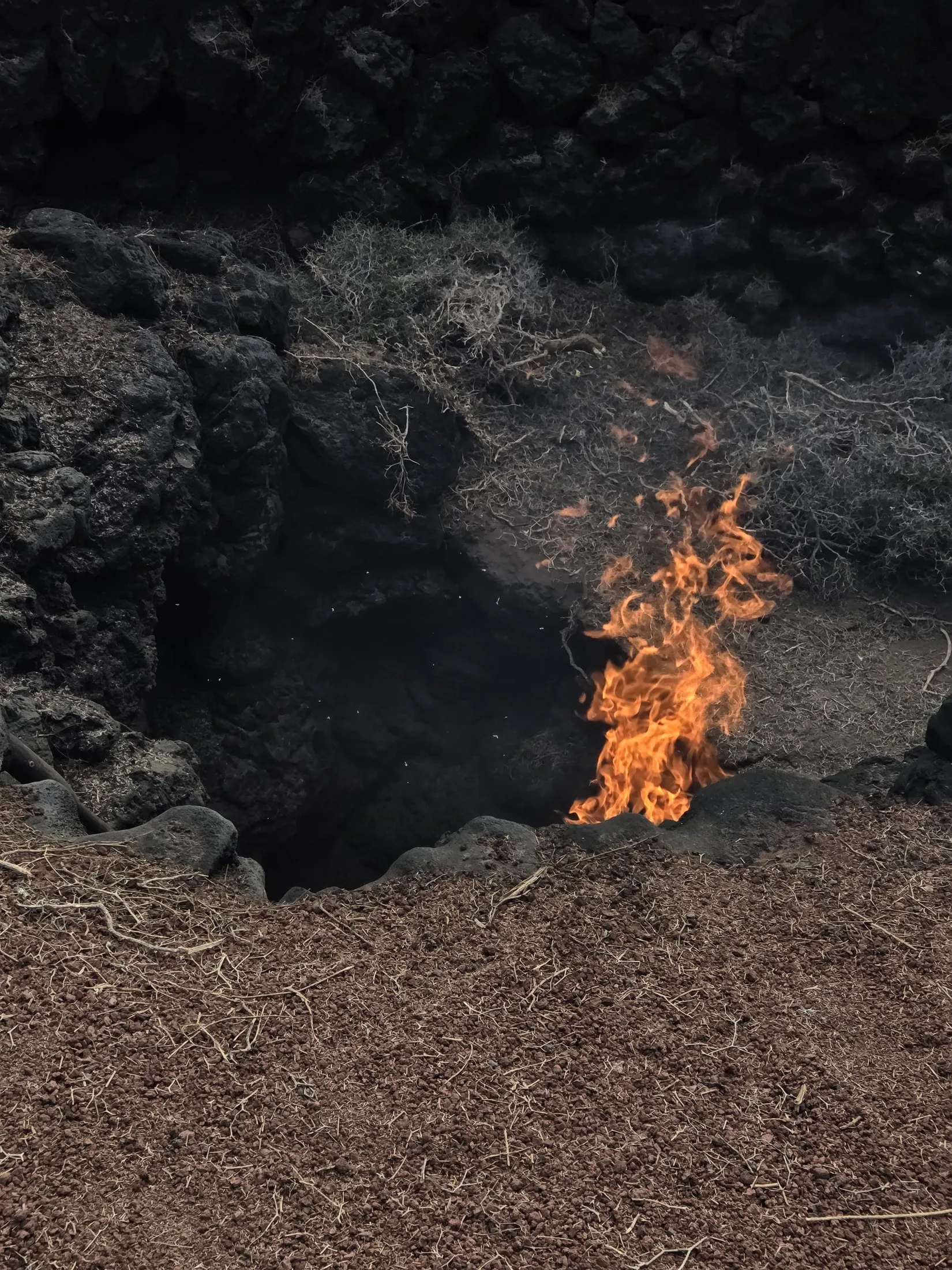 A small flame at the mouth of a volcanic hollow