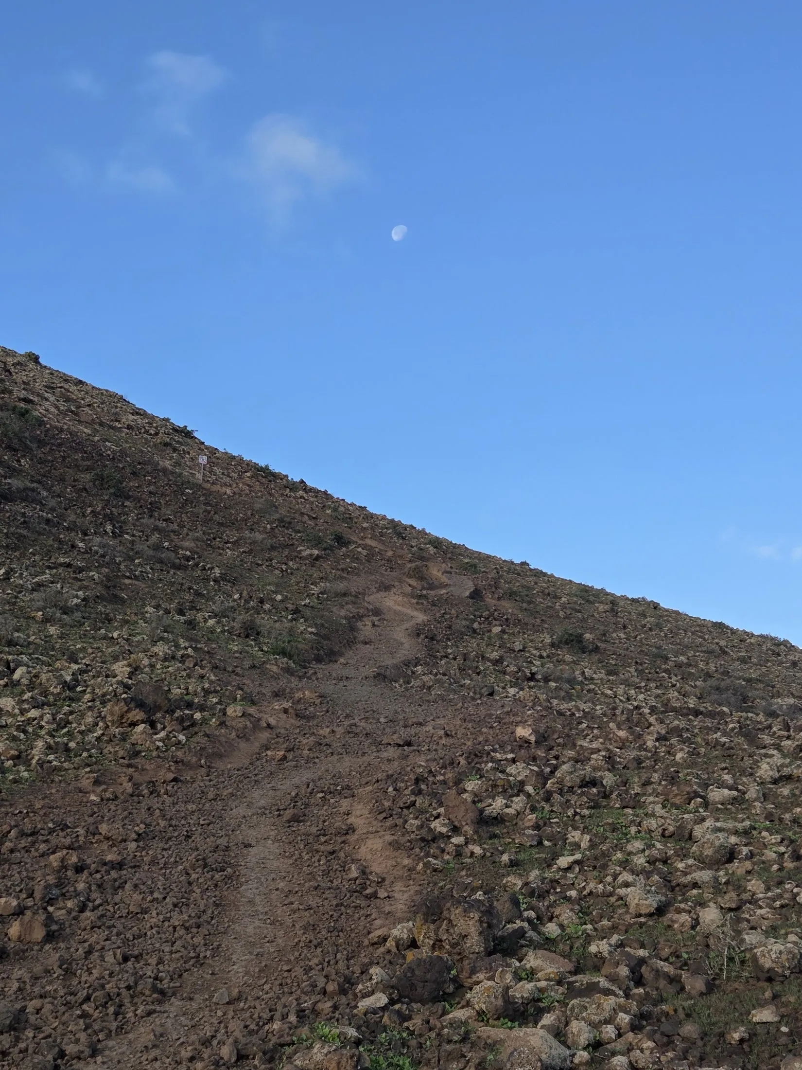 A faint path over a bare volcanic slope