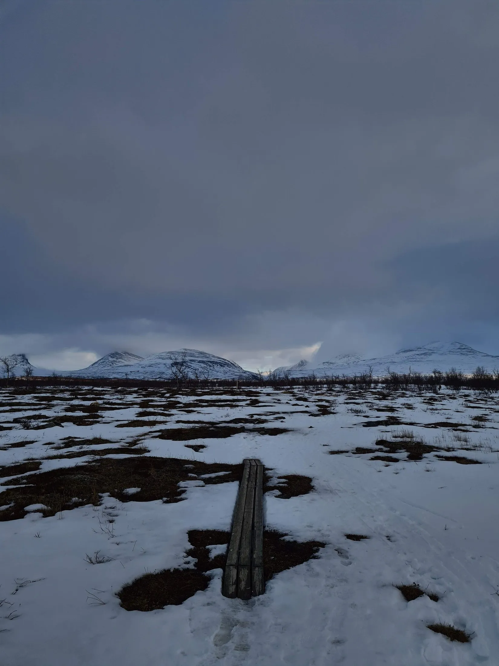 Dark water and snow under a heavy sky