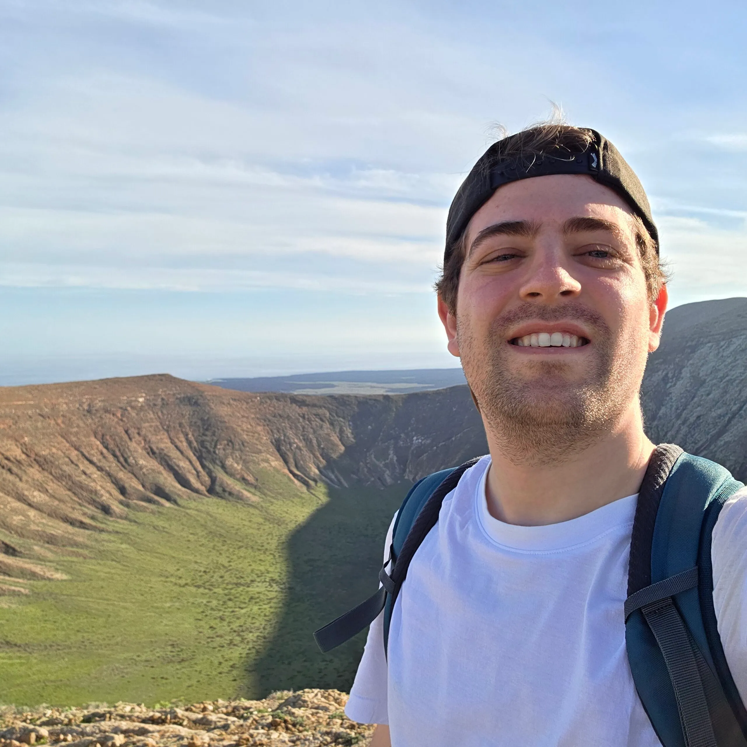Agus smiling outdoors, volcanic landscape behind him